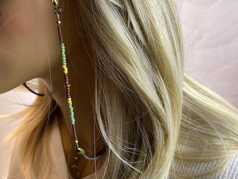 Eyeglass chain on a model. The beaded section is 6 inches on each side with a 15 section of leather that you can barely see. The leather rests on your neck for comfort. 
The beads are small, 8 mm in size.