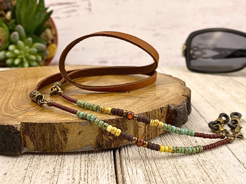 An eyeglass chain with Czech glass beads. Colors include turquoise, cream, dark brown and burnt orange. A 15 inch section of soft leather rests across your neck. The hardware is bronze plated brass. You can choose your leather color.