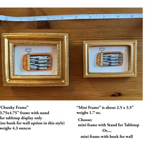 May include: Two gold-framed art pieces featuring a sardine can illustration. The larger frame is 3.75x4.75 inches, and the smaller is about 2.5 x 3.5 inches. The text on the image says "Chunky Frame" and "Mini Frame".