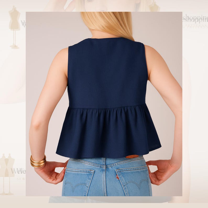 Op de afbeelding: Een mouwloze marineblauwe top met een peplum zoom, gecombineerd met lichtblauwe jeans. De top heeft een V-hals en een getailleerd lijfje dat uitloopt bij de taille. De persoon draagt een gouden armband.