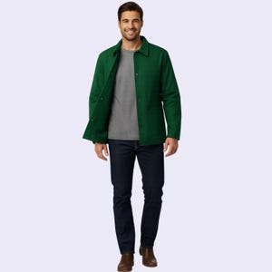May include: A person wearing a green jacket, gray t-shirt, and dark blue jeans. The jacket has a button-up front and two front pockets. The person is also wearing brown boots.