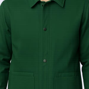 May include: A dark green jacket with a collar, two front pockets, and two visible buttons. The jacket is made of a smooth fabric and has a classic design. The jacket is a solid color and appears to be a medium weight.