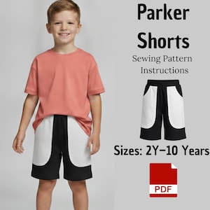 May include: A sewing pattern for Parker Shorts with instructions in PDF format. The design features black shorts with large white side pockets, suitable for sizes 2Y-10 Years. The image displays the shorts worn with a coral t-shirt.