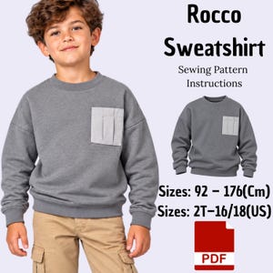Könnte beinhalten: Ein graues Sweatshirt mit einer hellgrauen Brusttasche und langen Ärmeln. Der Text lautet: Rocco Sweatshirt Sewing Pattern Instructions. Größen: 92-176(Cm), 2T-16/18(US). Ein rotes PDF-Symbol zeigt ein digitales Schnittmuster-Dokument an.
