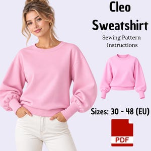 Puede incluir: Una sudadera de manga larga en color rosa claro con cuello redondo y puños fruncidos. El texto dice Cleo Sweatshirt Sewing Pattern Instructions, Sizes: 30 - 48 (EU) y PDF. El diseño presenta hombros caídos y un ajuste holgado.