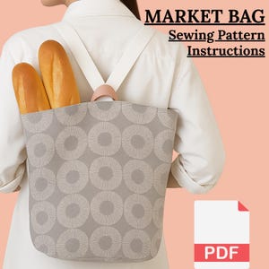 Puede incluir: Una bolsa de mercado gris con un patrón circular repetitivo, llevada en la espalda. La bolsa contiene dos barras de pan. La bolsa tiene correas blancas y un asa rosa. El texto en la imagen dice "MARKET BAG Sewing Pattern Instructions" y un icono PDF.