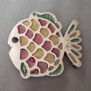 May include: A silver fish-shaped ornament with a hole for hanging. The fish features a mosaic design with red, yellow, and green accents. The tail and fins are detailed with green enamel.