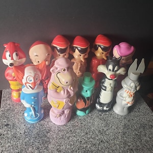 May include: A collection of vintage cartoon character figurines, including a red fox, a clown, a pink hippo, and Sylvester the Cat. The figurines are made of plastic and are in various colors.