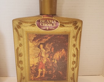 May include: A gold-colored glass bottle with a gold-colored stopper. The bottle has a label that says "Beam's Choice Aged 8 Years" and a picture of Charles I.