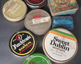Op de afbeelding: Een verzameling van acht vintage tabaksblikken in verschillende vormen en maten, met kleurrijke branding en tekst waaronder Barneys, Parsons Pleasure, Four Square, Players Navy Cut, Edgeworth, Punchbowle, Sweet Dublin en Chairman.