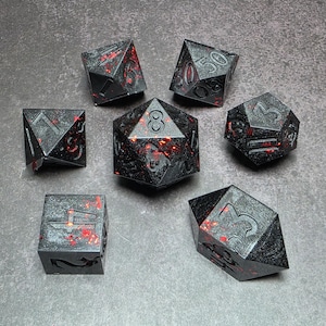 Op de afbeelding: Set van zeven zwarte polyhedrale dobbelstenen met rode accenten. Elke dobbelsteen heeft een unieke geometrische vorm en nummerindeling. De dobbelstenen zijn ontworpen voor tabletop-rollenspellen en hebben een getextureerd oppervlak.