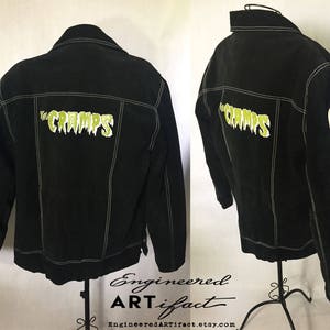 Pode incluir: Jaqueta de ganga preta com costuras brancas e patches bordados verdes que dizem "The Cramps" e "RIP Lux".