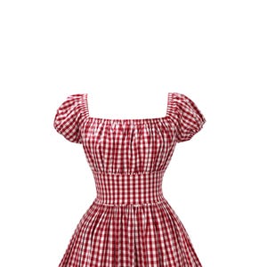 May include: A red and white gingham dress with a square neckline and short, puffed sleeves. The dress features a fitted bodice and a flared skirt, creating a classic, feminine silhouette. The fabric has a checkered pattern.