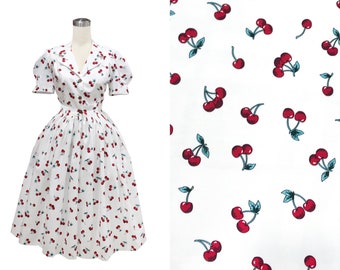 Könnte beinhalten: Ein weißes Kleid mit kurzen Ärmeln und einem Kirschendruck. Das Kleid hat einen taillierten Oberteil und einen vollen Rock.