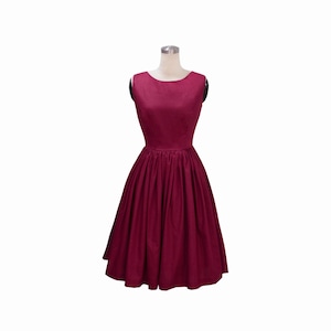 May include: A sleeveless, knee-length dress in a deep burgundy color. The garment features a round neckline, a fitted bodice, and a full, pleated skirt that flares out from the waistline. The fabric has a subtle sheen and a smooth texture.