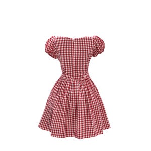 May include: A red and white gingham dress with a fitted bodice and a flared skirt. The dress features short, puffed sleeves and a zipper closure down the back. The fabric has a classic checkered pattern.