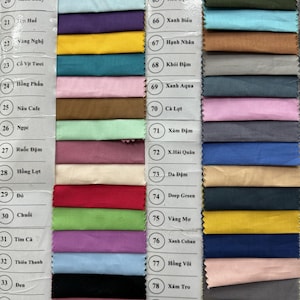 May include: A fabric swatch color chart featuring a wide array of rectangular textile samples arranged in columns. Each swatch is labeled with a corresponding number and text identifier, showcasing a diverse palette of solid colors including reds, blues, greens, yellows, pinks, browns, and grays.