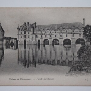 Puede incluir: Postal en blanco y negro del Château de Chenonceaux, Francia. El castillo histórico se refleja en el agua, con puentes de arco y una torre prominente. El texto "Château de Chenonceaux - Façade méridionale" es visible.