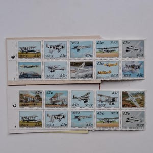 Op de afbeelding: Twee stroken vintage postzegels met verschillende vliegtuigontwerpen. Elke postzegel is rechthoekig, met een waarde van 45c en de letters "RSA". De postzegels tonen tweedekkers, eendekkers en andere historische vliegtuigen.