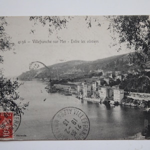 Può includere: Cartolina vintage in bianco e nero raffigurante una città costiera con edifici sul lungomare. La cartolina presenta un francobollo e un timbro postale, con il testo "4136 - Villefranche sur Mer - Entre les oliviers."