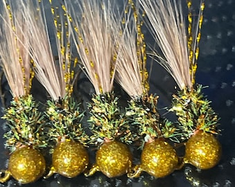 May include: Five gold and green fishing lures with brown and gold feathers. The lures have a round, shiny gold head.