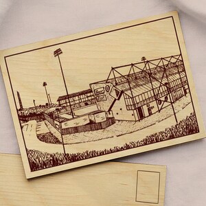Peut inclure: Illustration gravée sur bois d'un stade, probablement un lieu sportif, sur une plaque de bois rectangulaire. L'œuvre représente l'architecture du stade, y compris les tribunes et le toit. L'œuvre est probablement un objet décoratif ou un souvenir.