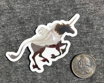 May include: A white unicorn sticker with a brown and white patterned design. The unicorn is running with its horn pointed forward. The sticker is on a gray background.