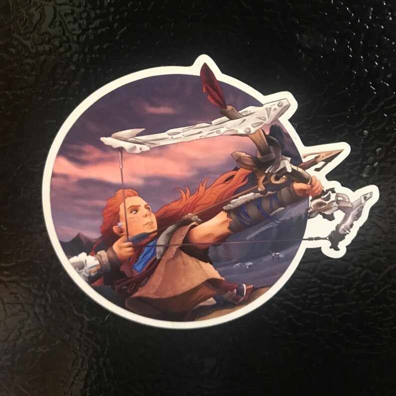 May include: A woman with red hair is holding a bow and arrow. She is wearing a brown leather outfit and a blue scarf. The background is a sunset sky with clouds.