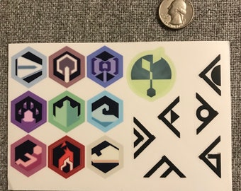 May include: A sheet of stickers with various colorful hexagonal designs and black triangle shapes. The stickers feature geometric patterns and symbols.