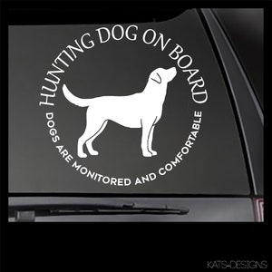 May include: White vinyl sticker with a black silhouette of a Labrador Retriever and the text "Hunting Dog On Board Dogs Are Monitored And Comfortable".