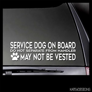 May include: White text on a black background reads 'SERVICE DOG ON BOARD DO NOT SEPARATE FROM HANDLER MAY NOT BE VESTED' with a paw print icon to the left of the last line of text. The text is on a car window.