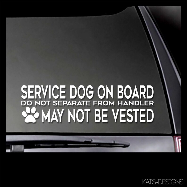 May include: White text on a black background reads 'SERVICE DOG ON BOARD DO NOT SEPARATE FROM HANDLER MAY NOT BE VESTED' with a paw print icon to the left of the last line of text. The text is on a car window.
