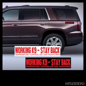 May include: A burgundy SUV with a black and white sticker that reads "WORKING K9 - STAY BACK TEMPERATURE CONTROLLED AND MONITORED" on the rear bumper. The sticker is repeated on the lower bumper. The word "MAGNET" is written in red on the rear window.