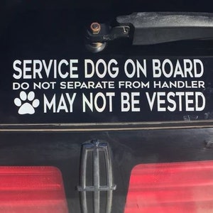 May include: A black car bumper with a white sticker that reads "SERVICE DOG ON BOARD." Below the text are the words "DO NOT SEPARATE FROM HANDLER" and "MAY NOT BE VESTED." A paw print graphic is also included.