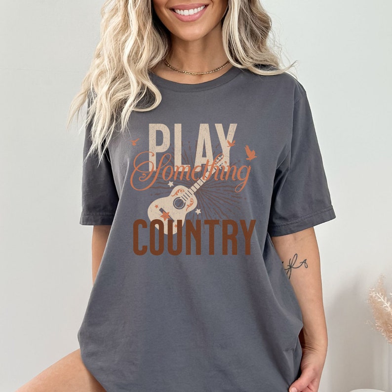 May include: Gray t-shirt with a vintage-style graphic of a guitar and the text "PLAY SOMETHING COUNTRY".
