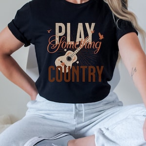 May include: Black t-shirt with a vintage-style graphic of a guitar and the text "PLAY SOMETHING COUNTRY".