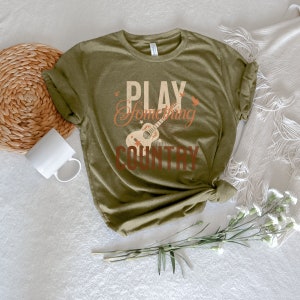 May include: A green t-shirt with the text "Play Something Country" and a vintage-style guitar graphic.