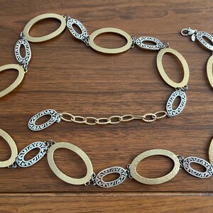 Puede incluir: Un collar dorado y plateado con eslabones ovalados. El collar presenta eslabones ovalados dorados y plateados alternos, conectados por eslabones de cadena dorados m&aacute;s peque&ntilde;os. El cierre es plateado.