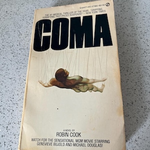 Peut inclure: Livre de poche vintage intitulé "COMA" de Robin Cook. La couverture présente une figure suspendue par des fils. La couverture du livre comprend également le texte "The #1 Medical Thriller of the Year..." et "Watch for the sensational MGM movie starring Genevieve Bujold and Michael Douglas!"