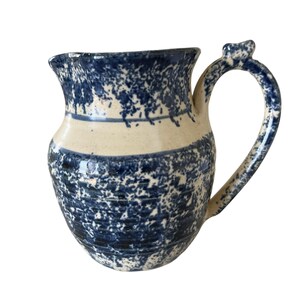 May include: A blue and white ceramic jug with a speckled glaze. The jug has a wide mouth and a handle.