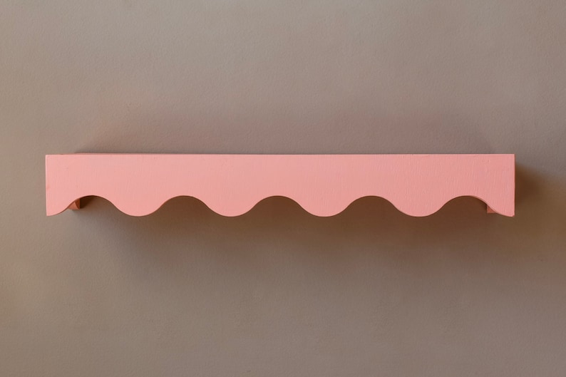 Peut inclure: Une &eacute;tag&egrave;re rose &agrave; bord festonn&eacute;. L'&eacute;tag&egrave;re est en bois et peinte d'une couleur rose clair.