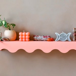 Peut inclure: Une &eacute;tag&egrave;re rose avec un bord festonn&eacute;, d&eacute;cor&eacute;e d'une plante en pot, d'une petite bougie orange, d'un bouquet de sauge, d'une bougie triple lune argent&eacute;e et d'une petite bouteille en verre remplie de fleurs s&eacute;ch&eacute;es.