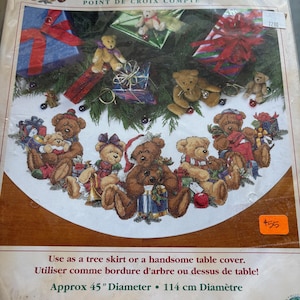 May include: A Dimensions counted cross stitch kit for a Christmas Bears tree skirt. The design features several teddy bears with Christmas decorations. The kit includes cotton thread, Aida cloth, a needle, and instructions. The diameter is approximately 45 inches.