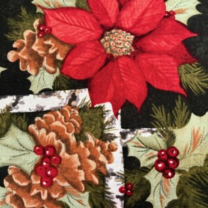 May include: A festive fabric featuring a repeating pattern of a large red poinsettia flower, brown pine cones, and sprigs of green holly with red berries. The background is a dark green and white grid pattern, creating a holiday theme.