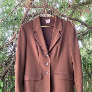 Könnte beinhalten: Ein brauner Blazer mit einem einzigen Knopfverschluss und zwei Taschen. Der Blazer hat ein Etikett mit der Aufschrift "Blevo".