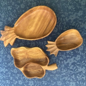 Könnte beinhalten: Drei Holzschalen in Form von Ananas. Die Schalen sind aus hellem braunem Holz gefertigt und haben eine natürliche Oberfläche.
