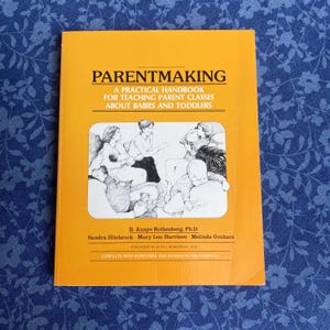 May include: An orange book titled "PARENTMAKING" with the subtitle "A Practical Handbook for Teaching Parent Classes About Babies and Toddlers." The cover features a black and white illustration of parents and babies. The author's names are listed below the illustration.