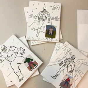 May include: Five blank canvas panels with black and white line drawings of superheroes. The panels feature Batman, Hulk, Spiderman, and a smaller image of Batman. The panels are labeled "Art by Gagan".