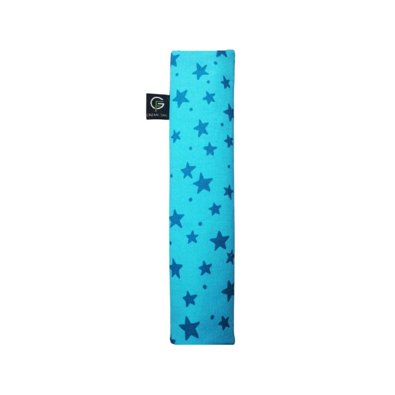 Puede incluir: Una correa rectangular de tela en color turquesa brillante con un patr&oacute;n repetitivo de estrellas azul oscuro y peque&ntilde;os puntos. Una peque&ntilde;a etiqueta de tela negra est&aacute; unida al lateral, mostrando el texto blanco GF y la palabra CREATIONS.