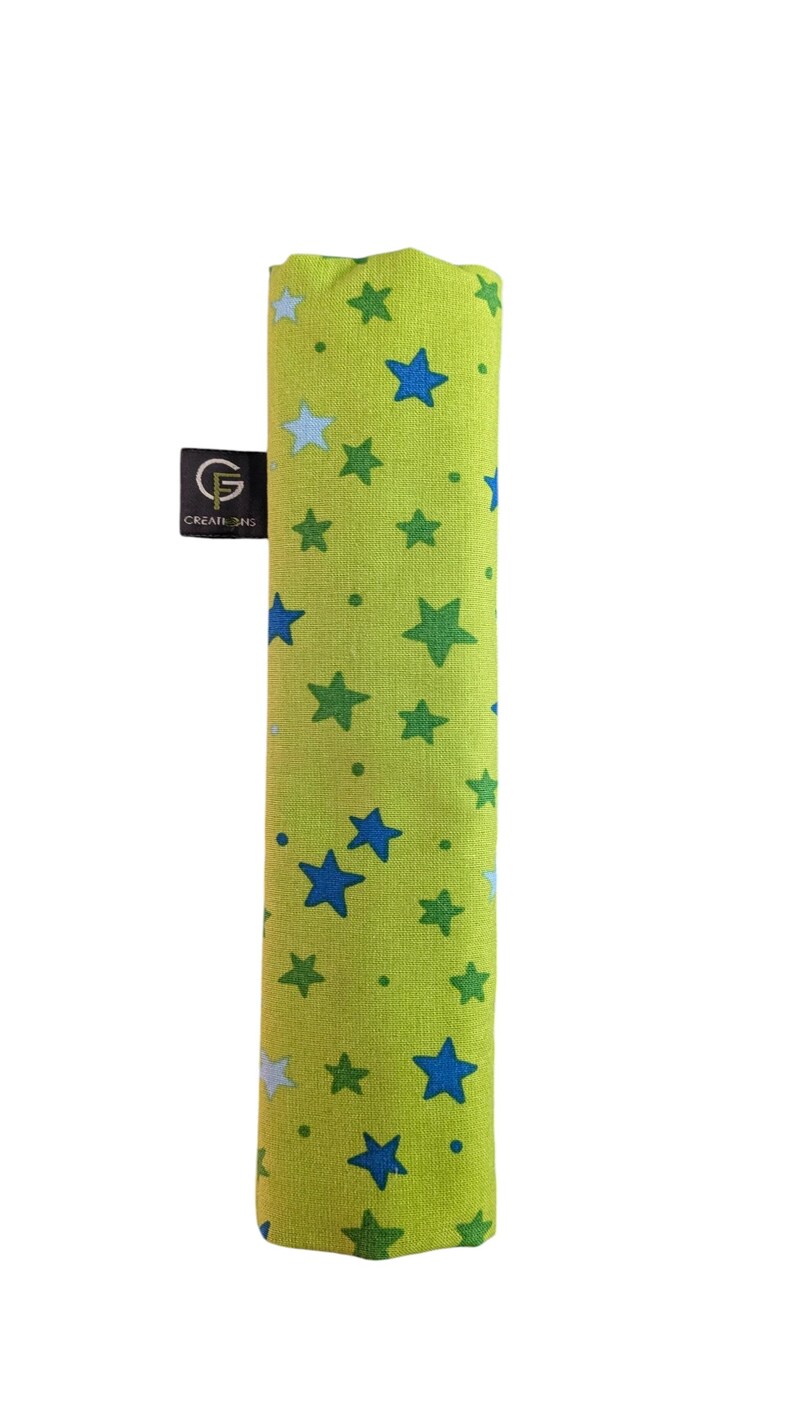 Puede incluir: Una funda de tela rectangular en color verde lima con un patr&oacute;n disperso de estrellas azules, verde oscuro y azul claro. Una peque&ntilde;a etiqueta de tela negra en el lateral muestra un logotipo blanco con el texto G CREATIONS en un dise&ntilde;o circular.
